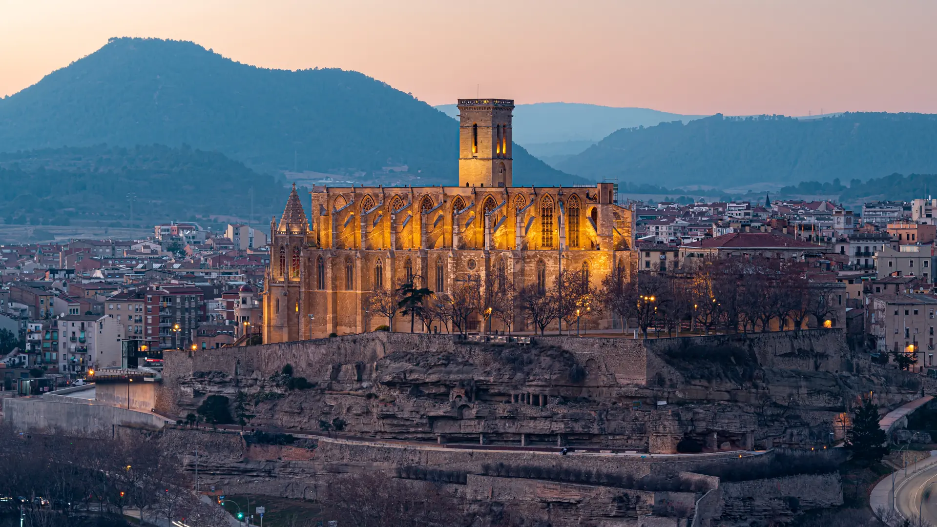 La Seu de Manresa iluminada al atardecer, sobre el casco antiguo y con la sierra al fondo